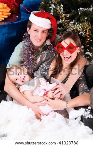 Christmas theme: happy family in Santas caps sitting together on a snow.