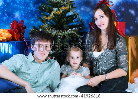 Christmas theme: happy family sitting together on a snow.