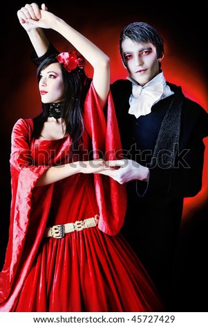 Portrait of a beautiful dancing couple in medieval costumes with vampire style make-up. Shot in a studio.