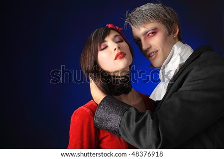 Portrait of a beautiful couple in medieval costumes with vampire style make-up. Shot in a studio.