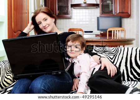 Happy woman with her son is looking at a laptop at home.