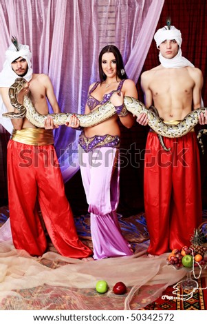 Shot of young people in oriental costumes posing with a python.