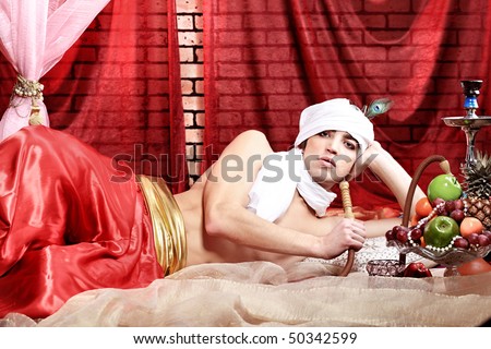 Shot of a man in oriental costumes having a rest and smoking hookah.