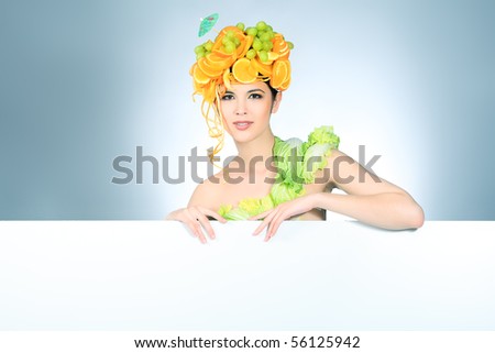 Shot of a beautiful young woman with fruits headwear holding white board. Food concept, healthcare.
