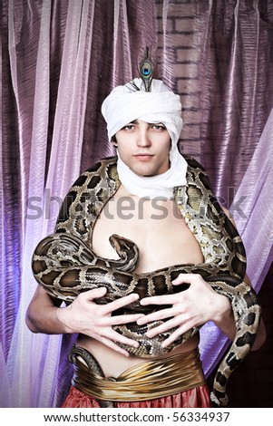 Shot of a man in oriental costume holding a python.