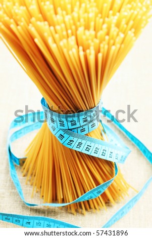 Food concept: bunch of uncooked spaghetti tied with tape measure.