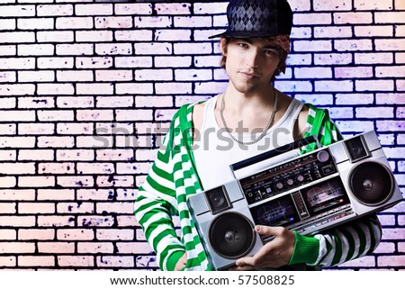 Trendy young man posing  against a brick wall with tape recorder.
