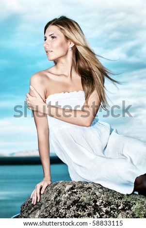Beautiful young woman posing over sea and mountains.
