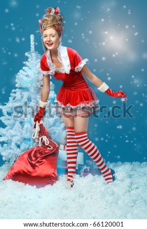 Fashionable young woman in Santa Claus clothes with presents over black background.