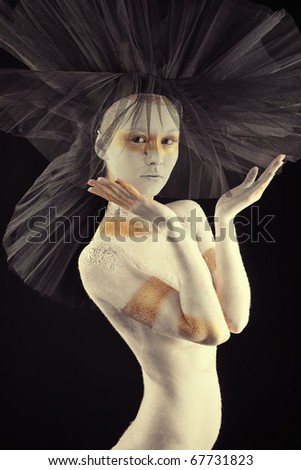 Artistic woman painted with  white and bronze colors, over black background. Body painting project.