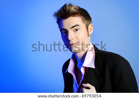 Young man dressed in rock\'n\'roll style, posing over blue background.