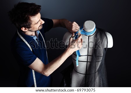 Portrait of a man fashion designer working with dummy at studio.