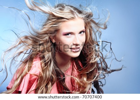 Portrait of a beautiful woman with flying hair. Studio shot over grey background.