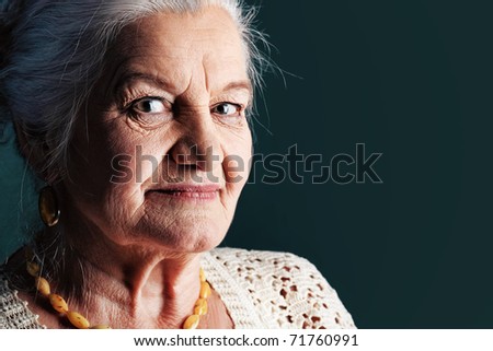 Portrait of a smiling senior woman. Studio shot over grey background.