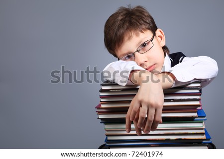 Educational theme: portrait of a schoolboy with books. Studio shot over grey background.