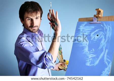 Portrait of an artist painting on easel. Shot in a studio.