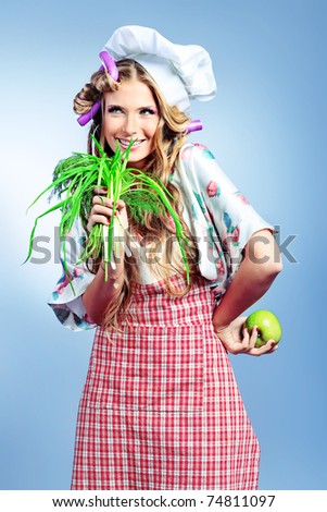 Beautiful blonde woman housewife holding greens and fruits. Studio shot over grey background.