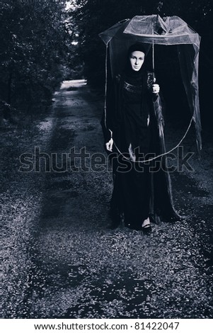Shot of a sad woman in mask wearing old-fashioned  black dress.