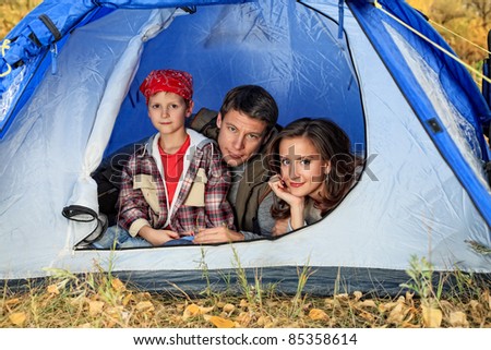 Happy family having a rest outdoor in tent.