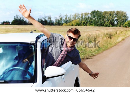 Handsome young man having summer trip on a car.