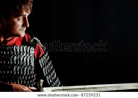 Portrait of a medieval male knight in armor over black background.
