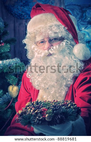 Santa Claus posing with presents over Christmas background.