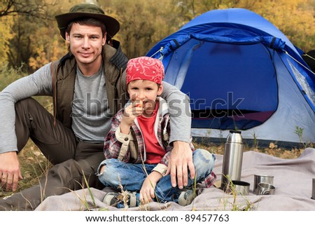 Happy father with his son having a rest outdoor in tent.