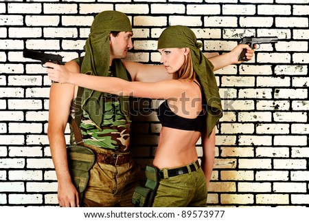 Shot of a military couple posing against brick wall.