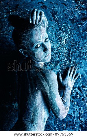 Portrait of an artistic woman painted with clay. Shot in a studio.