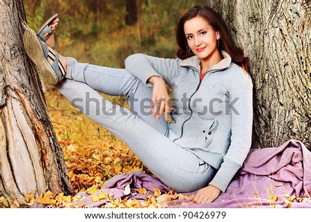Happy young woman having a rest outdoor in the autumn park.