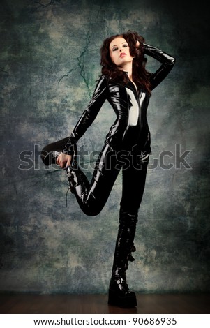 Fashion shot of a woman in black glossy overall and platform boots.