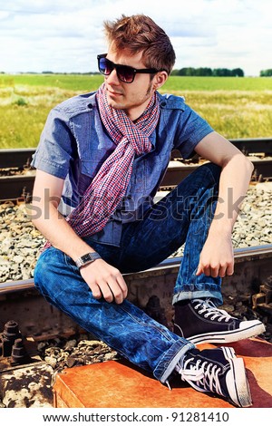 Portrait of a handsome young man posing at a railroad.