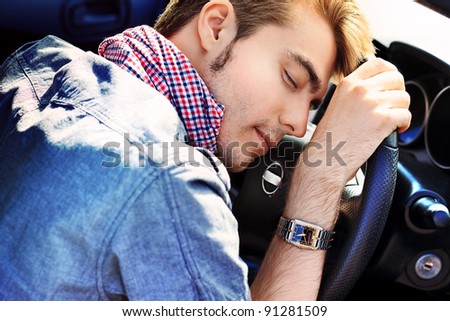 Young man is sleeping in a car.