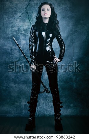 Fashion shot of a woman in black glossy overall and platform boots.