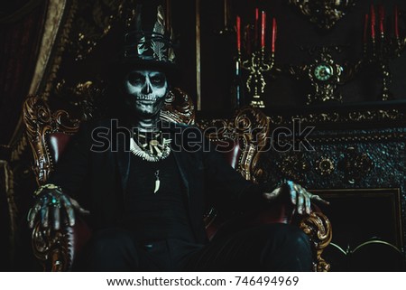 Halloween. A man with a skull makeup dressed in a tail-coat and a top-hat is in the old castle. Baron Saturday. Baron Samedi. Dia de los muertos. Day of The Dead. Old vintage interior.