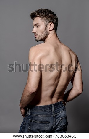 Portrait of a sexy young man with muscular body posing at studio. Gray background. Men\'s health.