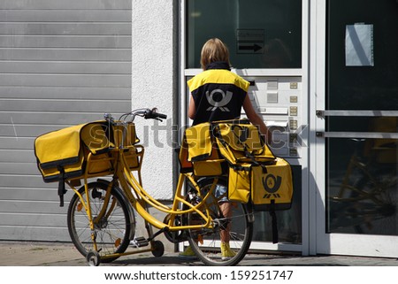 DUESSELDORF, GERMANY - JULY 8: Typical German Postwoman with their yellow Bicycle distributes mail six days a week in Dusseldorf, Germany on July 8, 2010