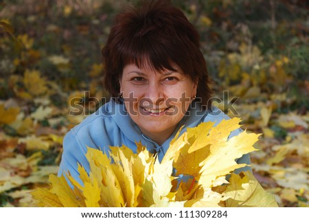 pretty women pick up of leaves in autumn park