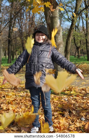 pretty child pick up of leaves in autumn park