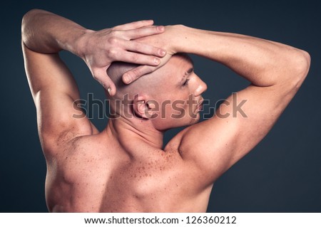 Portrait of naked athletic man posing over gray background