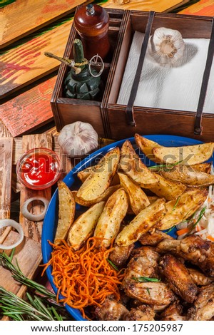 Big plate with fried chicken wings, potato and marinated carrot and cabbage