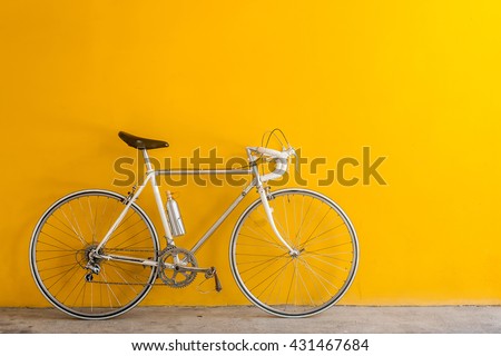 The vintage  hybrid bicycle parking against yellow wall