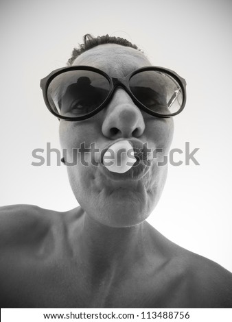 Caricature girl with sunglasses chewing gum, from bellow with wide angle lens / black and white monochrome / funny girl