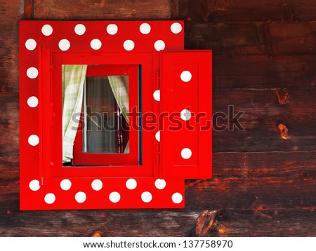 Red window with white polka dots in an wooden peasant house, ethnic house and window