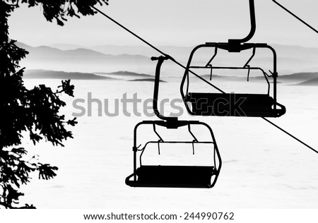 Ski lift chairs on bright winter day over the clouds, cableway funicular chair equipment, Garmisch Partenkirchen, Austria