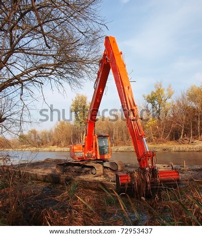 Orange coloured heavy construction digger / bulldozer clearing the river