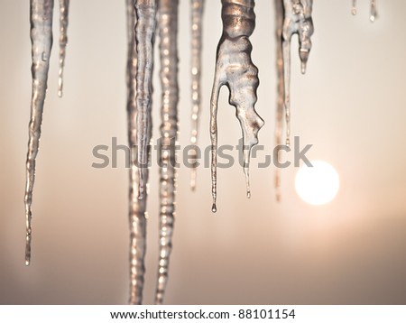 Thawing icicles isolated on blue with sun in background / face ice /