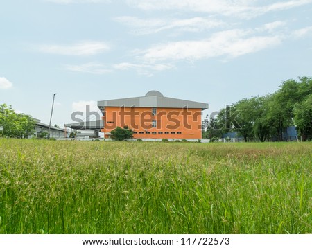 Orange small Office Building with Plant Arrangements Behind lawn.