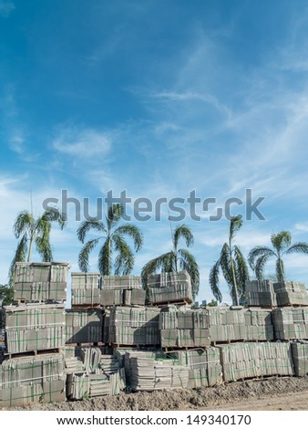 stack of concrete blocks, construction site against a blue sky with tree palm