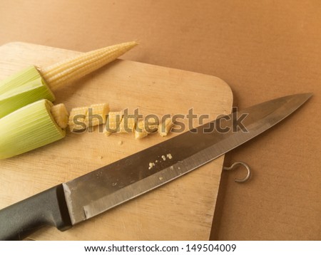 Cropped baby corn on cutting board with knife